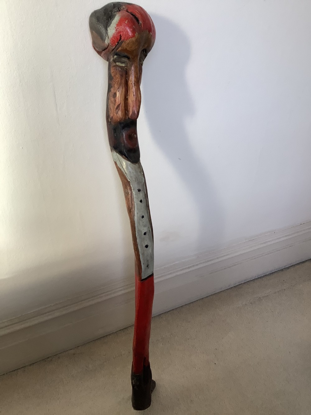 A hand-carved polychrome thorn wood walking stick featuring an anthropomorphic head and a painted red and grey shaft. View II