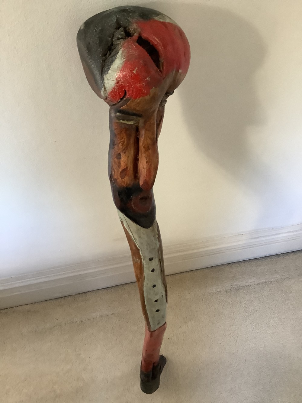 A hand-carved polychrome thorn wood walking stick featuring an anthropomorphic head and a painted red and grey shaft. View III