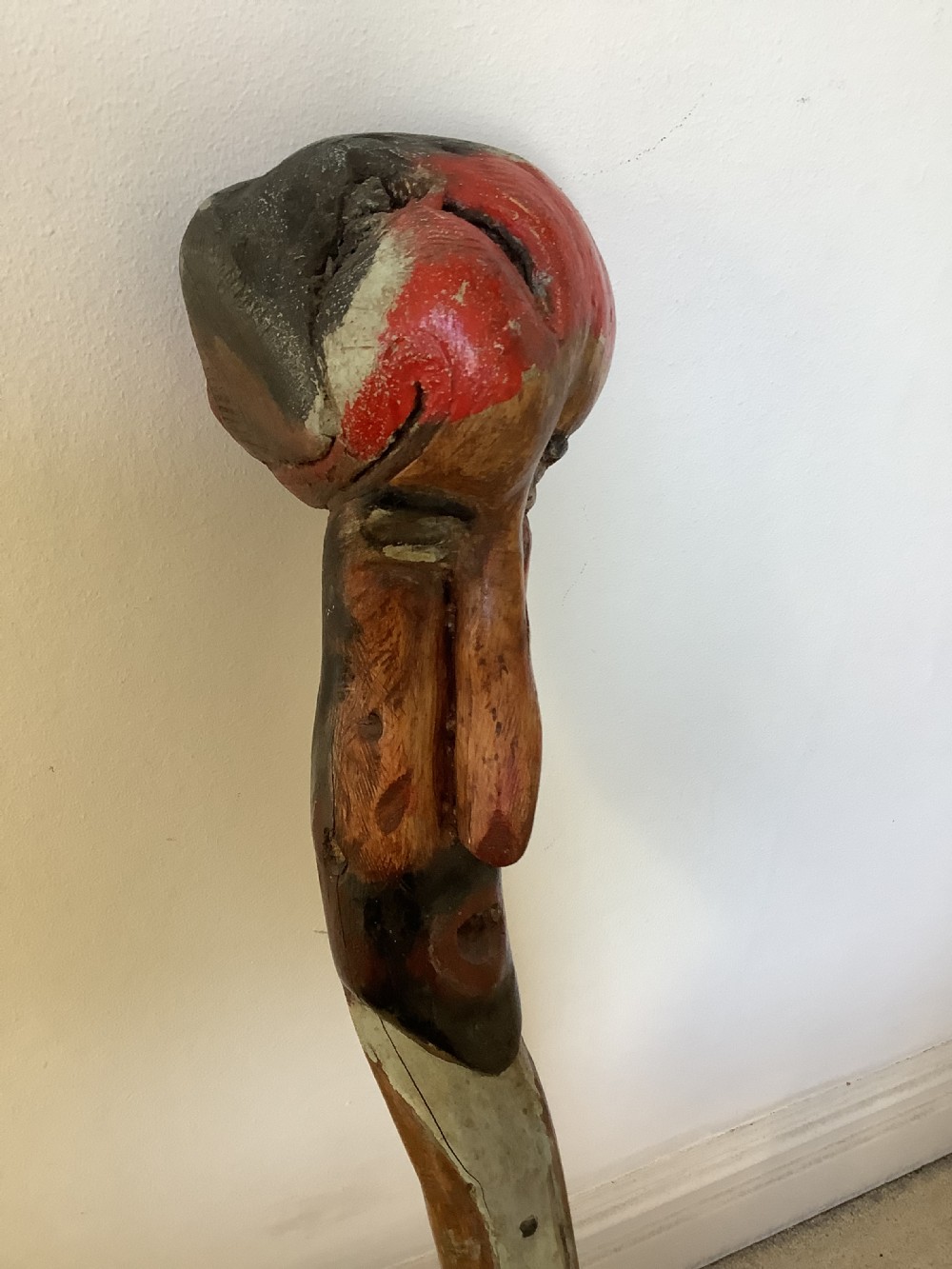 A hand-carved polychrome thorn wood walking stick featuring an anthropomorphic head and a painted red and grey shaft. View V