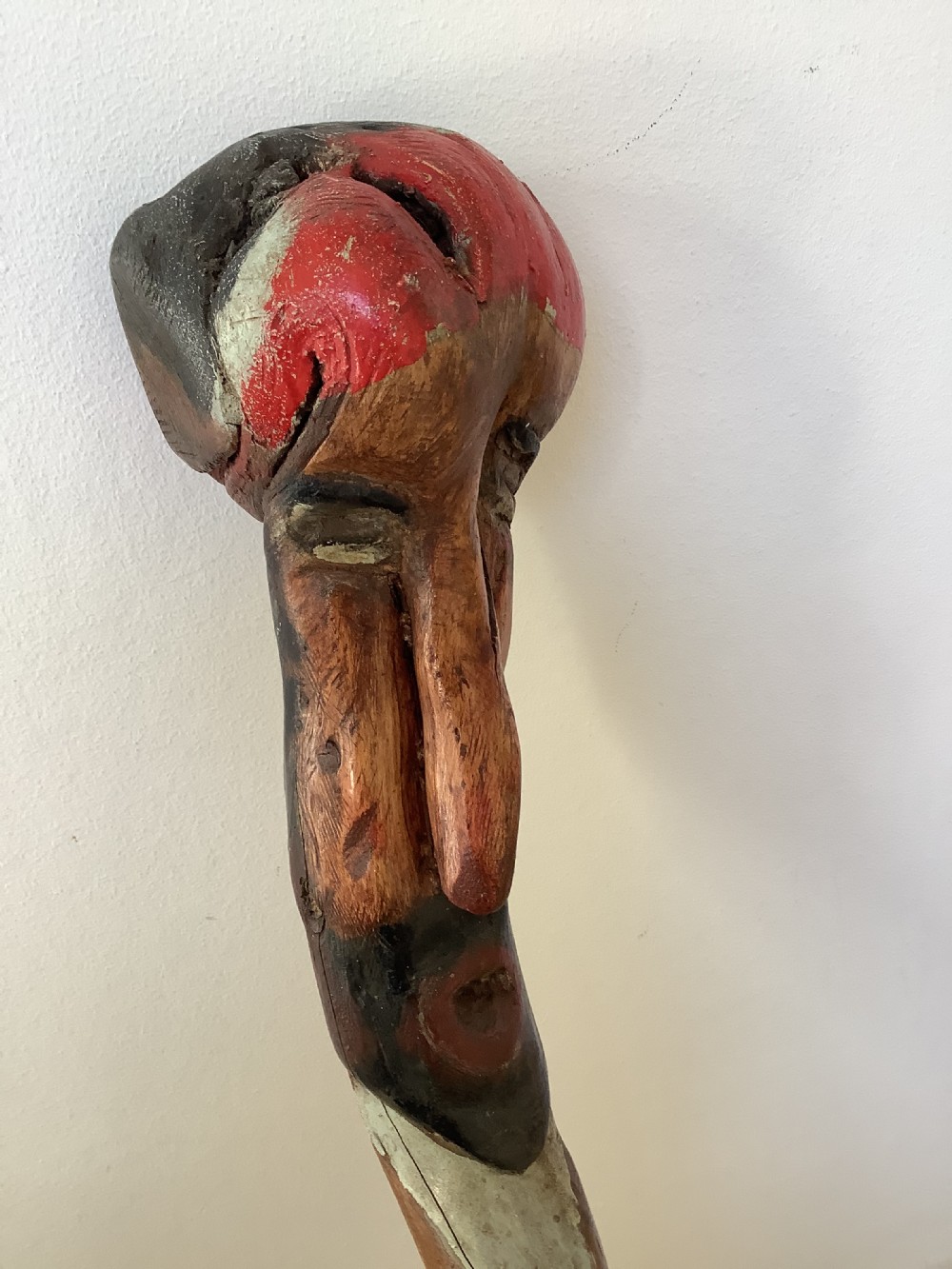 A hand-carved polychrome thorn wood walking stick featuring an anthropomorphic head and a painted red and grey shaft. View VII