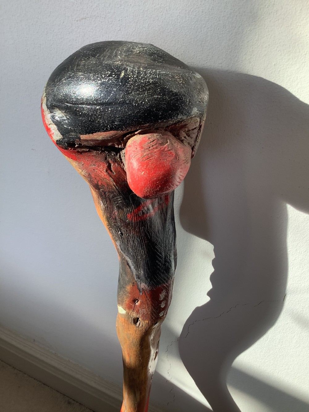 A hand-carved polychrome thorn wood walking stick featuring an anthropomorphic head and a painted red and grey shaft. View IX