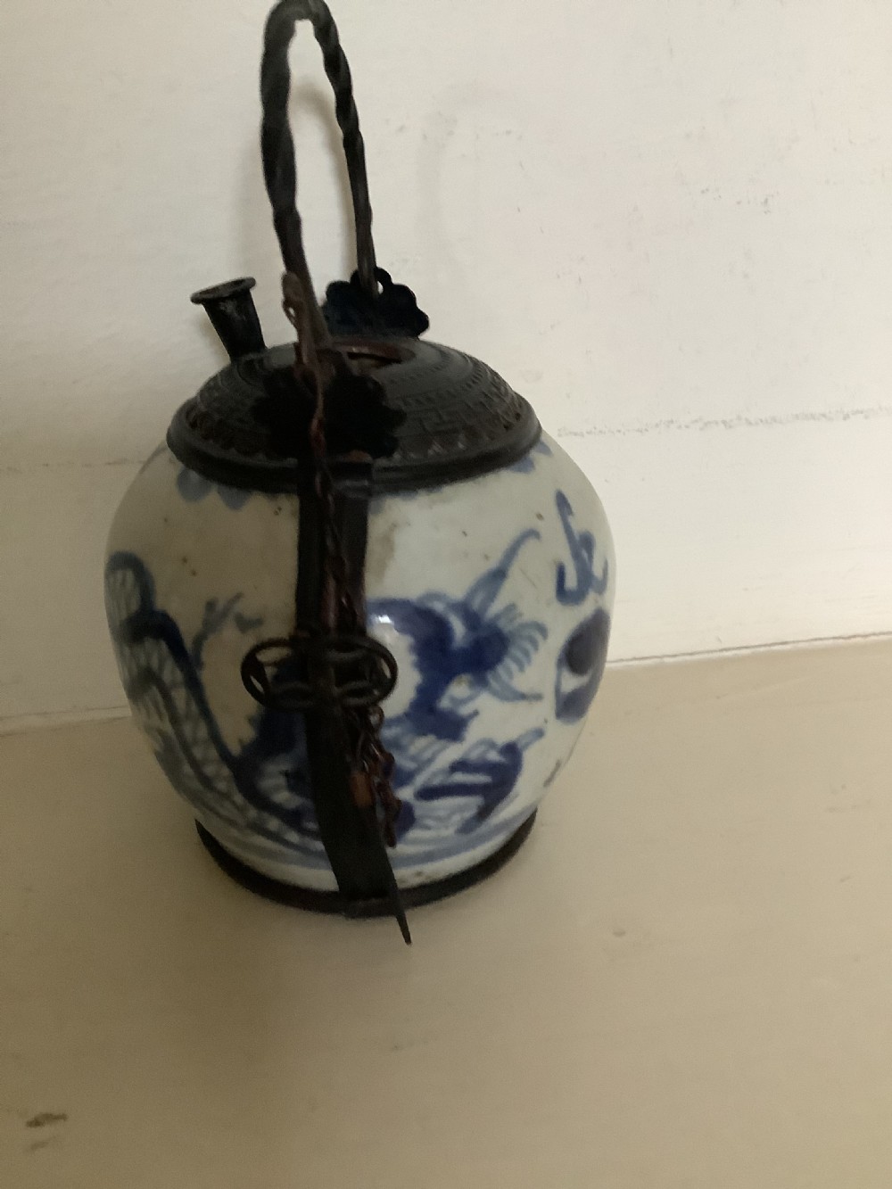 A small 19th-century Chinese blue and white porcelain pot featuring hand-painted motifs, enclosed in metal wire mounts with an attached stopper and handle. View III