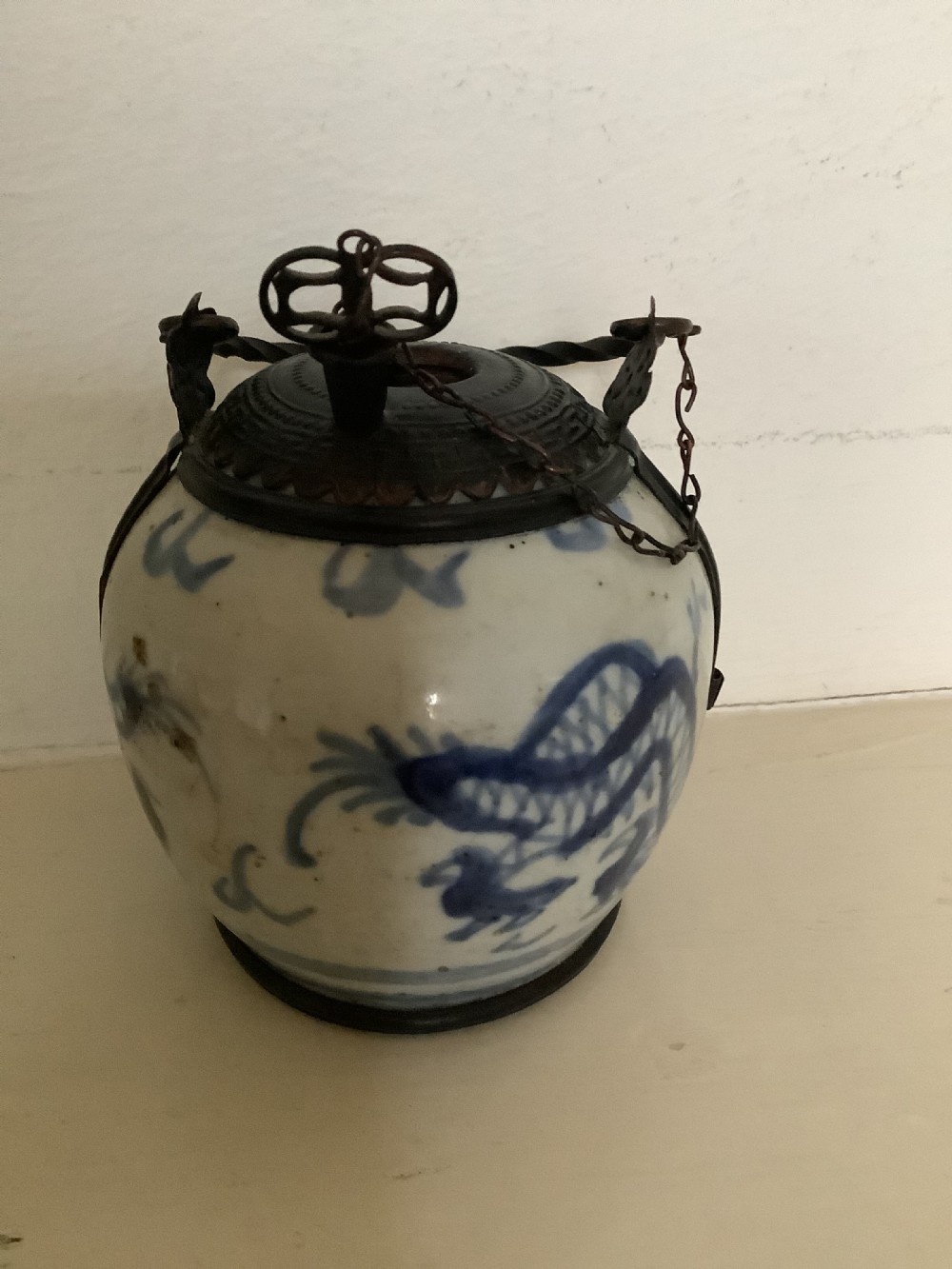 A small 19th-century Chinese blue and white porcelain pot featuring hand-painted motifs, enclosed in metal wire mounts with an attached stopper and handle. View IV