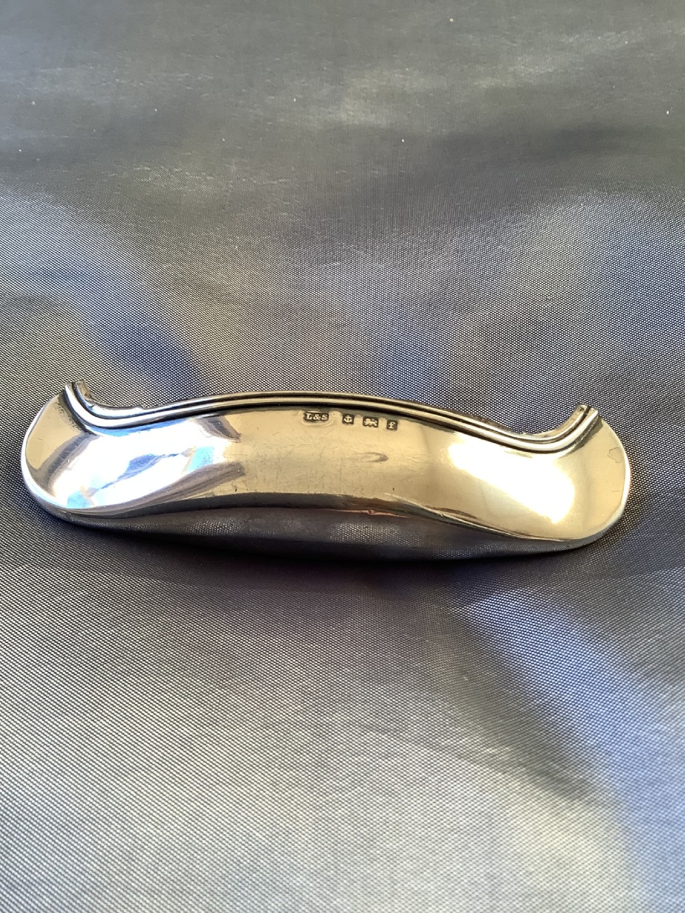 An Edwardian sterling silver pin cushion crafted in the form of a canoe with a dark fabric insert and visible hallmark stamps on the side. View III