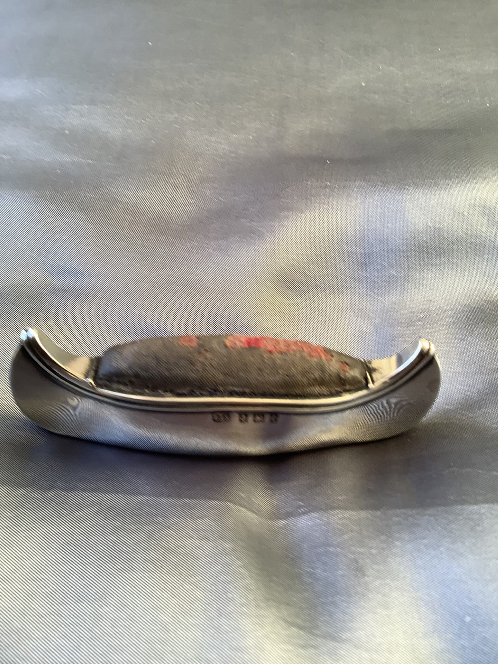 An Edwardian sterling silver pin cushion crafted in the form of a canoe with a dark fabric insert and visible hallmark stamps on the side. View IV