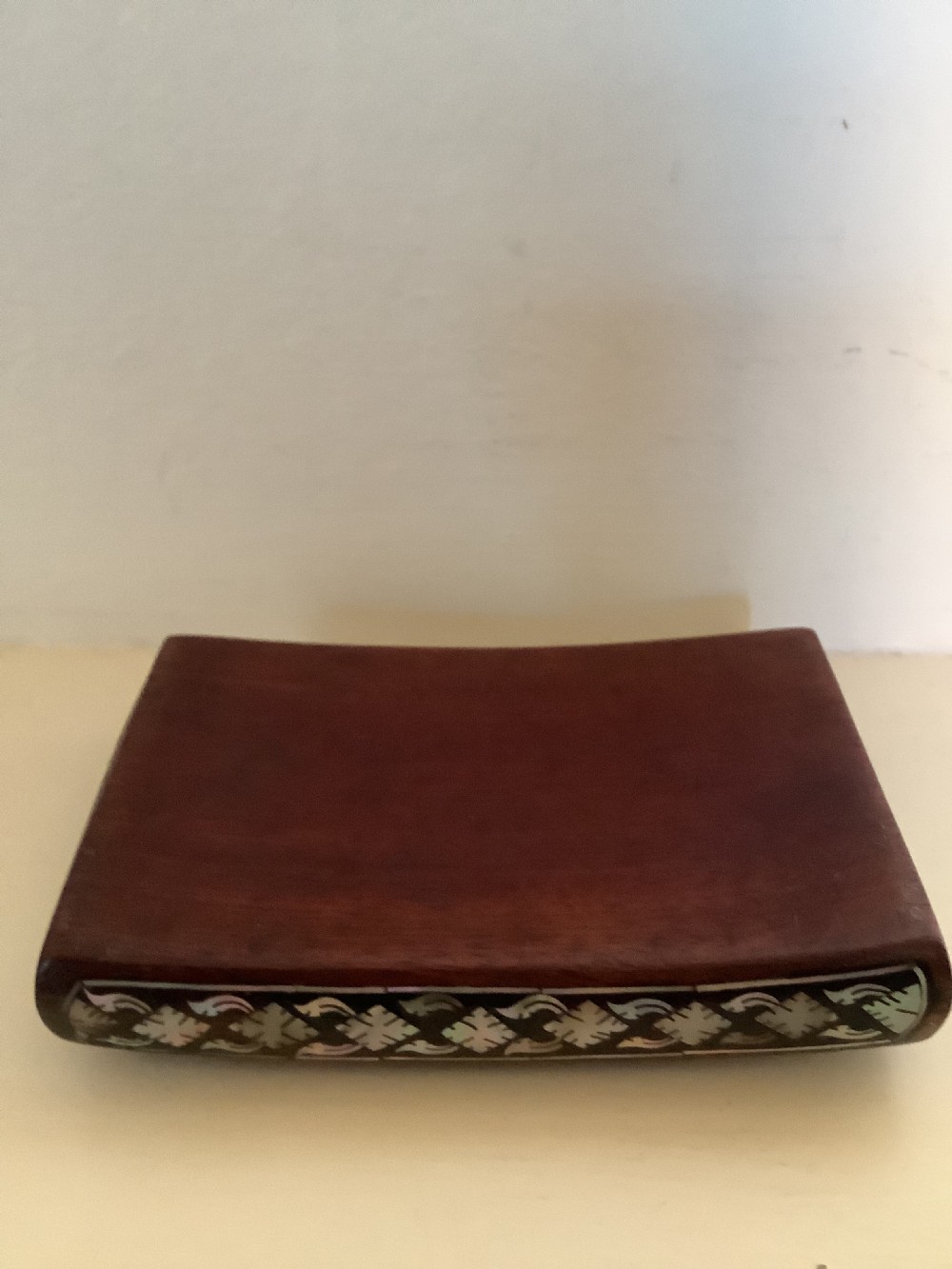 A rectangular dark hardwood box decorated with intricate mother-of-pearl inlay depicting a central serpent surrounded by floral scrolls and a geometric border. View VI