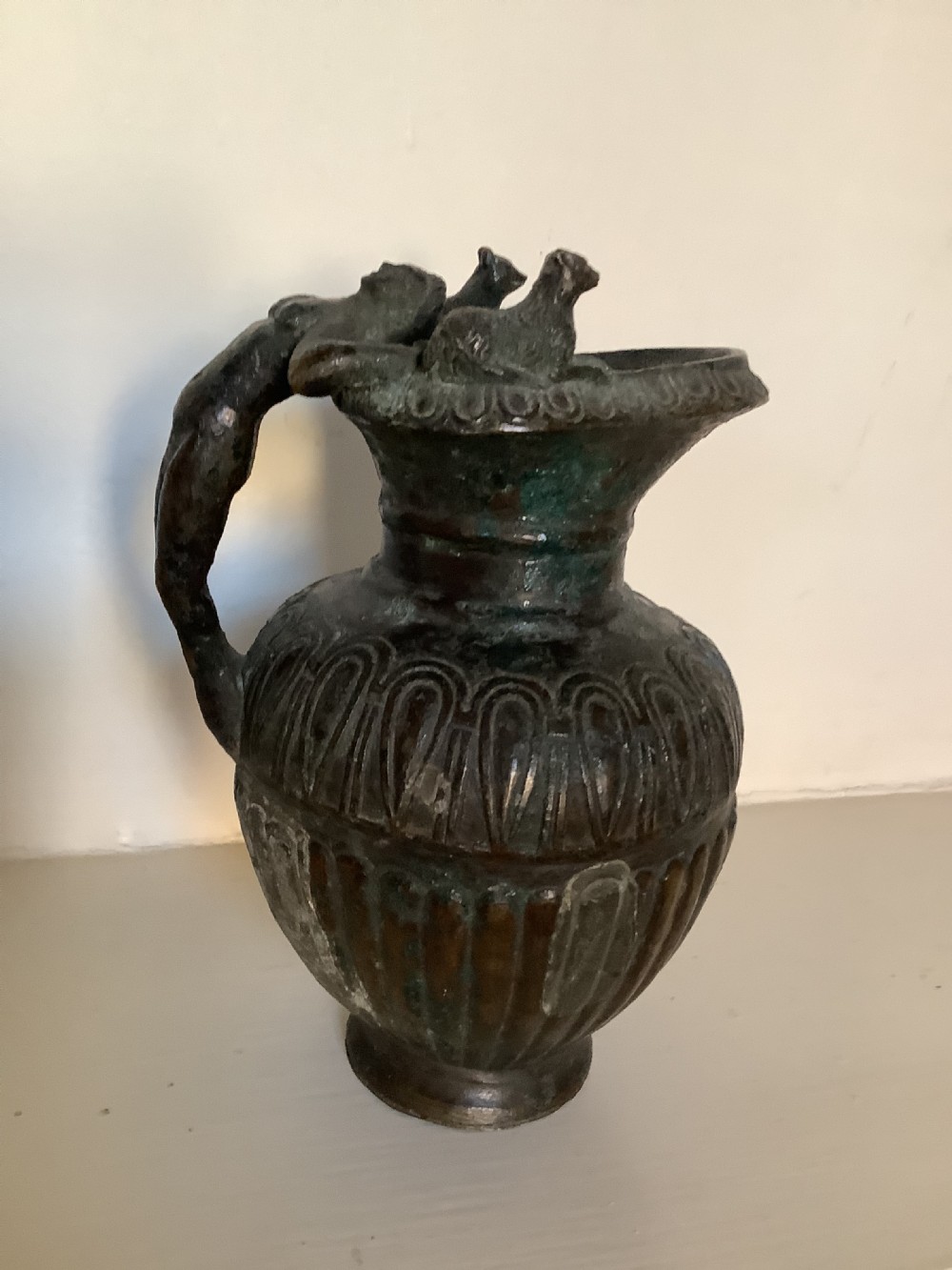 A heavily patinated bronze jug the handle depicting Dionysus God of wine and pleasure