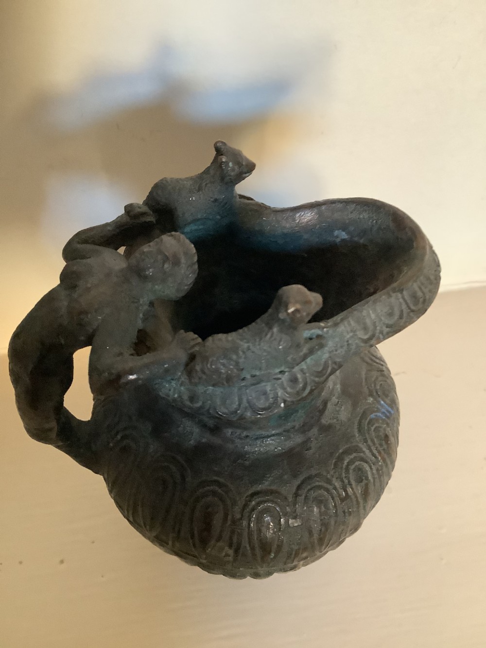 A patinated bronze jug with a flared fluted rim, a gadrooned body, and a sculpted handle depicting a mythological figure. View II