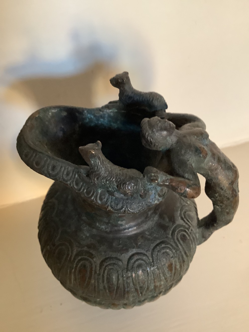A patinated bronze jug with a flared fluted rim, a gadrooned body, and a sculpted handle depicting a mythological figure. View III