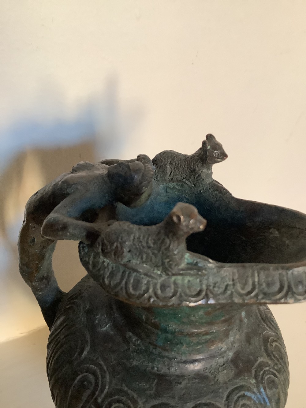 A patinated bronze jug with a flared fluted rim, a gadrooned body, and a sculpted handle depicting a mythological figure. View IV