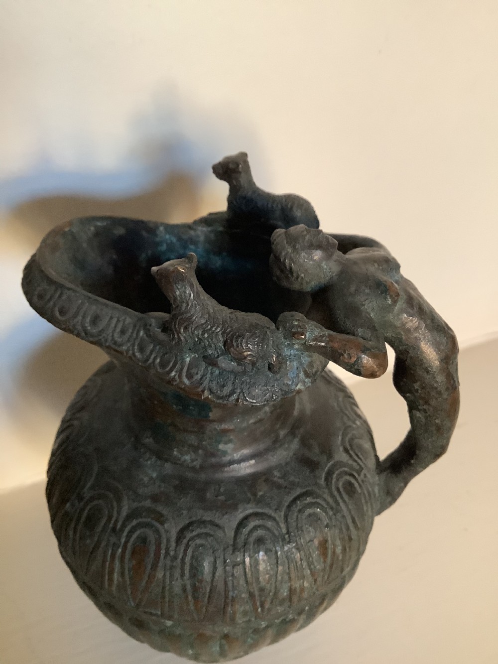 A patinated bronze jug with a flared fluted rim, a gadrooned body, and a sculpted handle depicting a mythological figure. View V