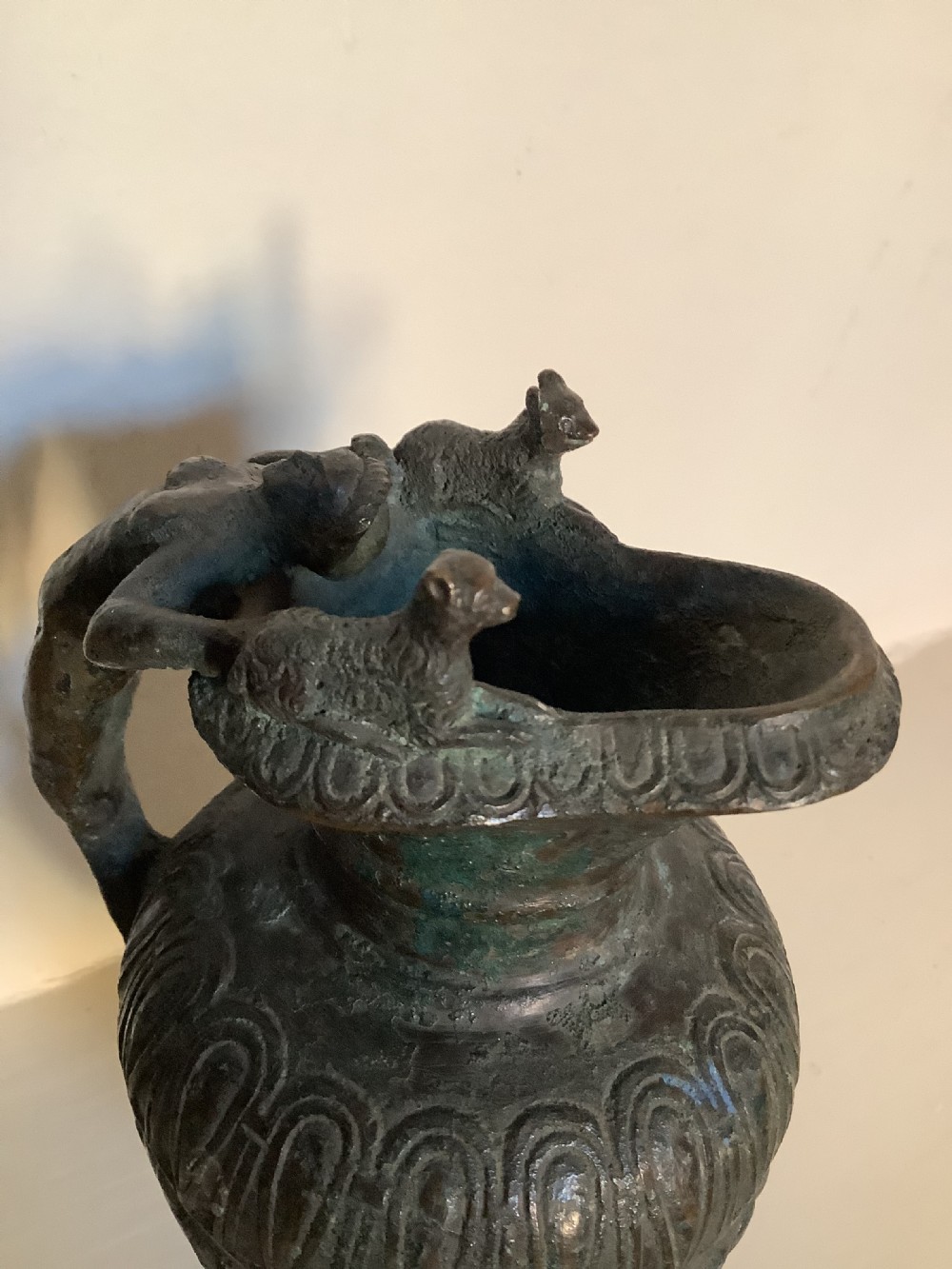 A patinated bronze jug with a flared fluted rim, a gadrooned body, and a sculpted handle depicting a mythological figure. View VI