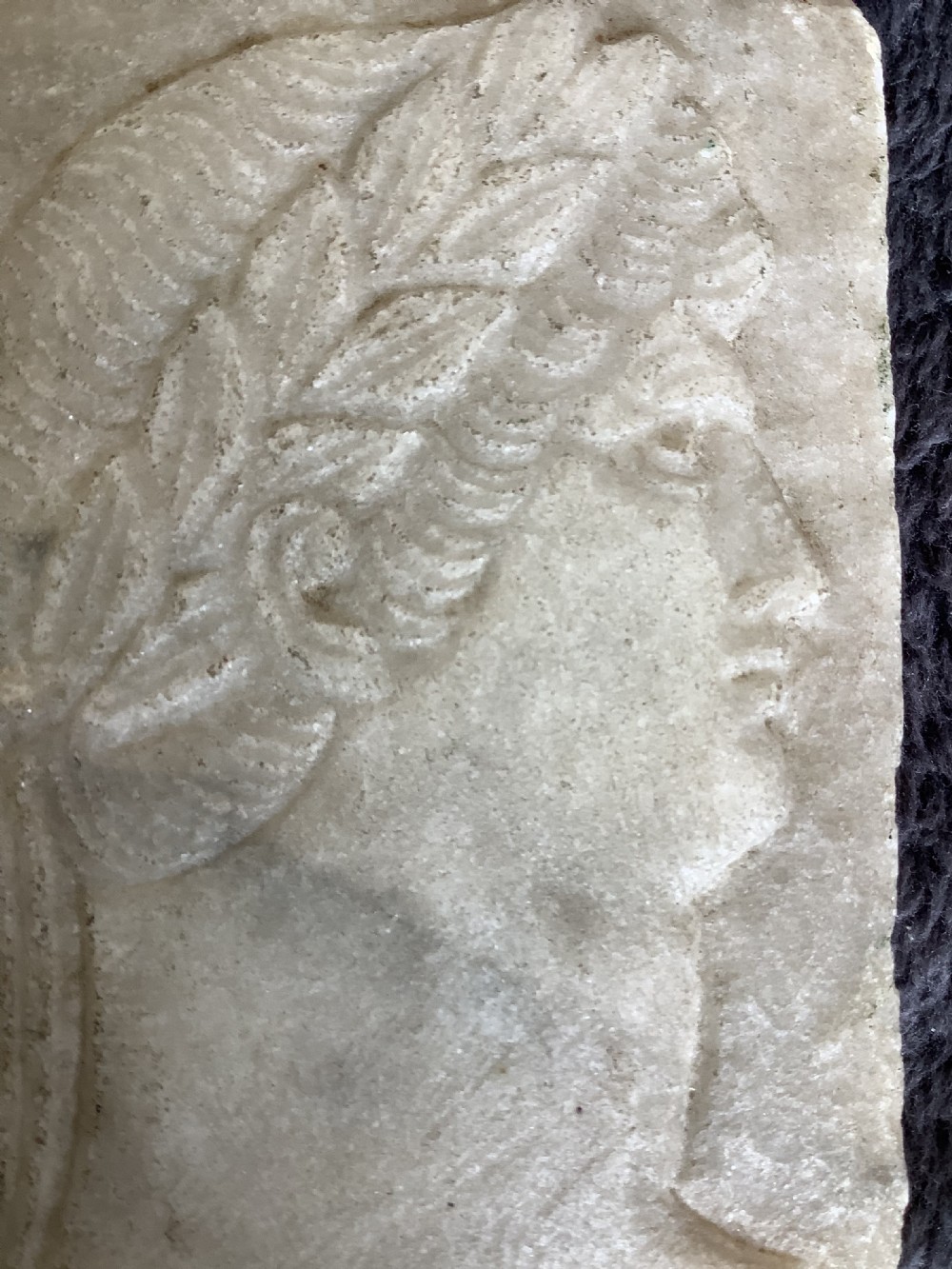 A rectangular carved marble plaque depicting the profile portrait of a Roman Emperor wearing a laurel wreath. View VI