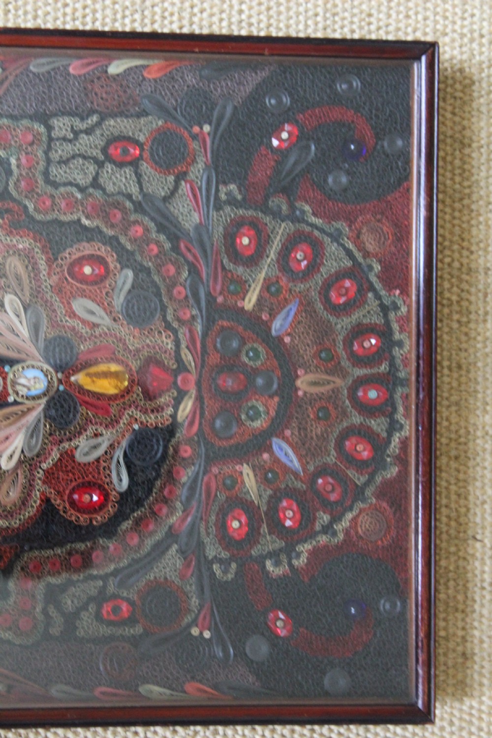 An antique framed 19th-century Indian quillwork picture featuring intricate red, black, and gold paper scrollwork embellished with beads and small painted portrait miniatures. View VII