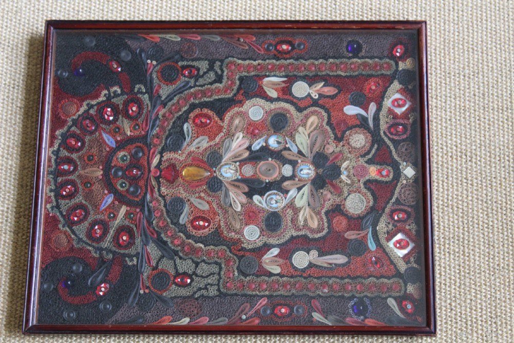 An antique framed 19th-century Indian quillwork picture featuring intricate red, black, and gold paper scrollwork embellished with beads and small painted portrait miniatures. View IX