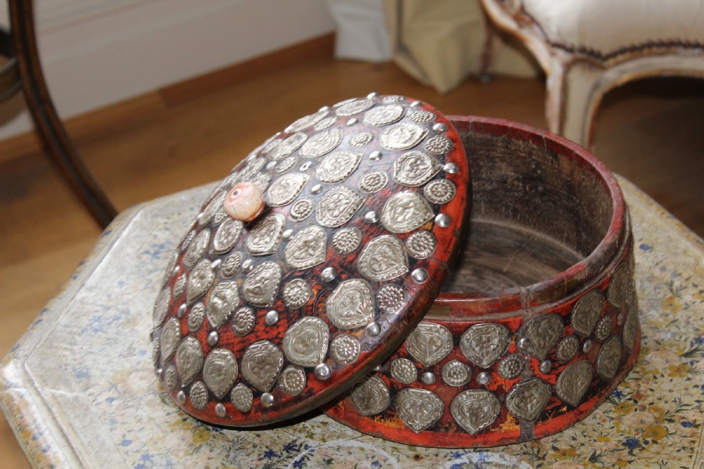 A circular red lacquered Kashmiri turban box with a domed lid, adorned with embossed silver-coloured metal mounts and a central turned knob. View III