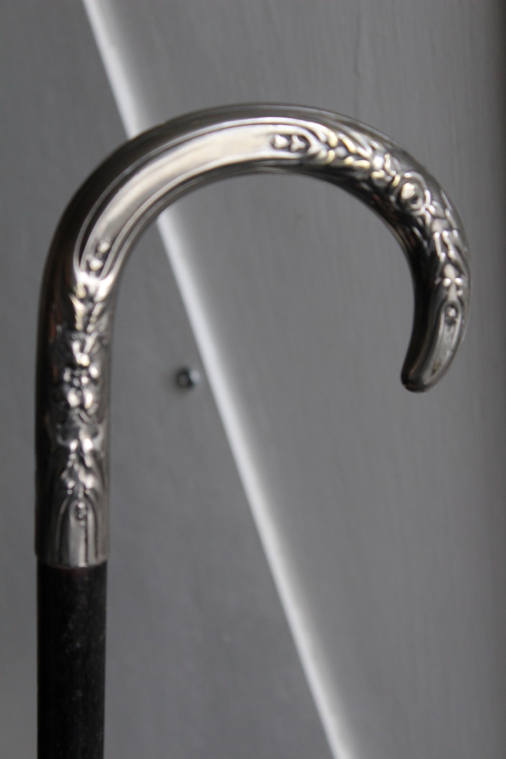 An ebonised oak walking stick featuring a silver-coloured crook handle embossed with floral and scroll patterns. View III