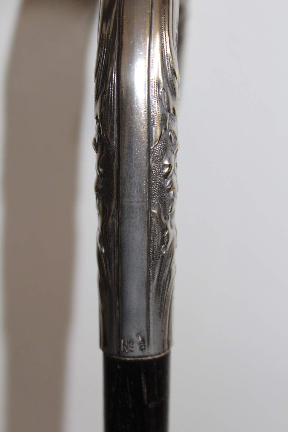 An ebonised oak walking stick featuring a silver-coloured crook handle embossed with floral and scroll patterns. View IV
