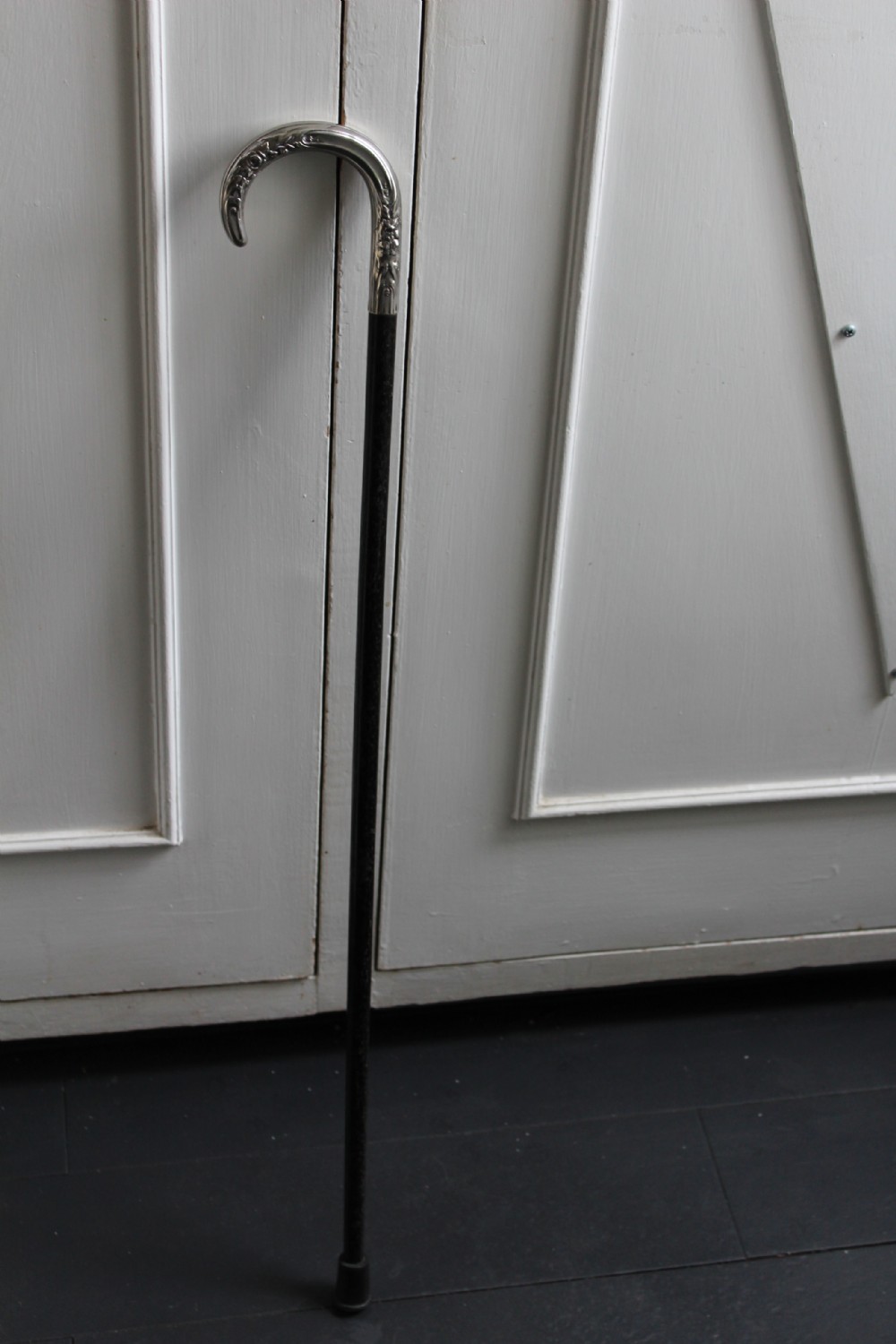 An ebonised oak walking stick featuring a silver-coloured crook handle embossed with floral and scroll patterns. View V