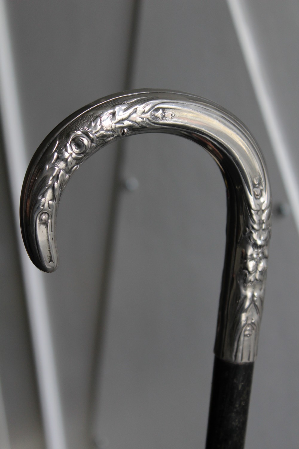 An ebonised oak walking stick featuring a silver-coloured crook handle embossed with floral and scroll patterns. View VII
