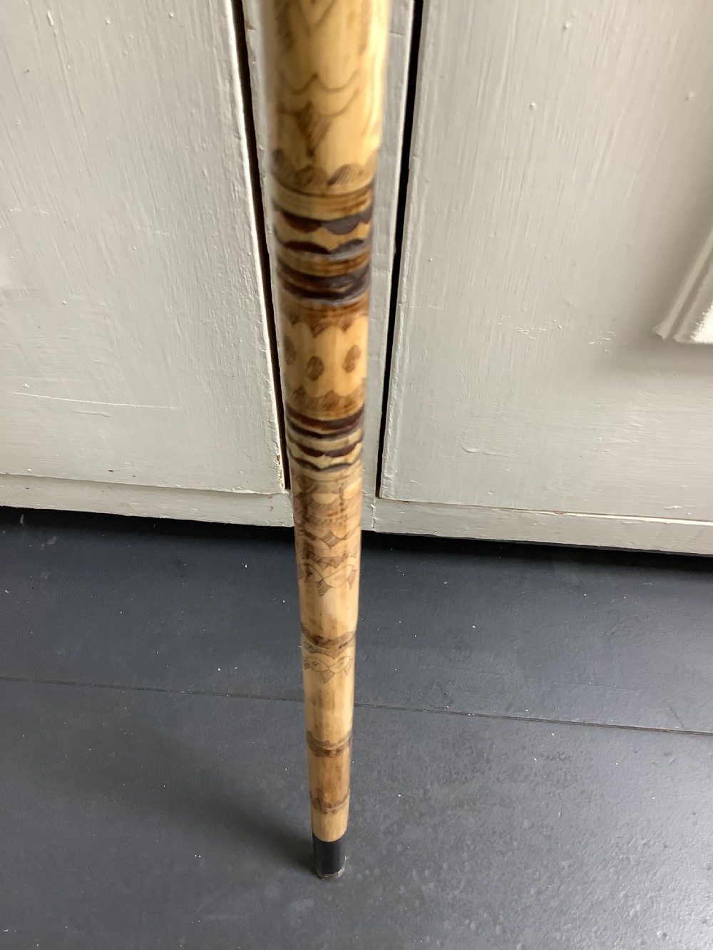 A maritime walking stick featuring a carved scrimshaw shaft with geometric patterns and a T-bar handle made of cream bone and black end caps. View VIII