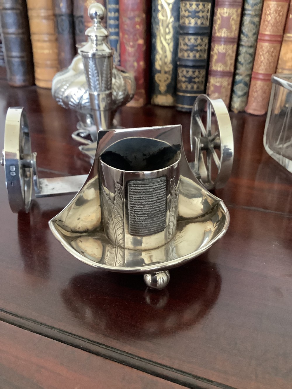 An antique silver and clear cut glass smoking compendium modelled in the form of a wheeled fire carriage with integrated lighter and storage compartments. View IV
