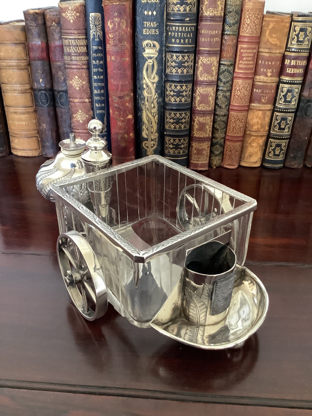An antique silver and clear cut glass smoking compendium modelled in the form of a wheeled fire carriage with integrated lighter and storage compartments. View IX