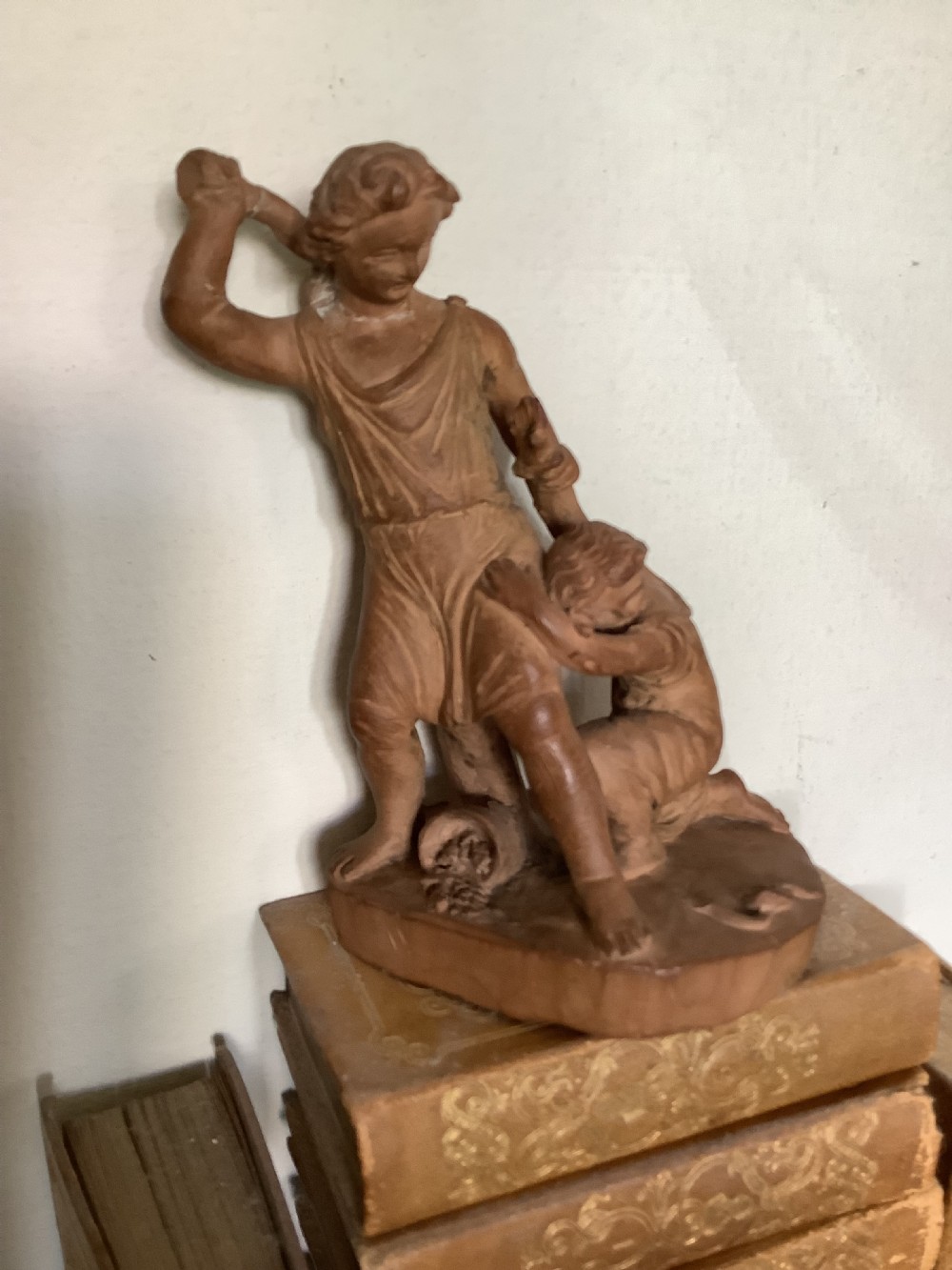 A 19th-century terracotta sculpture depicting two classical figures set on an integral oval base.