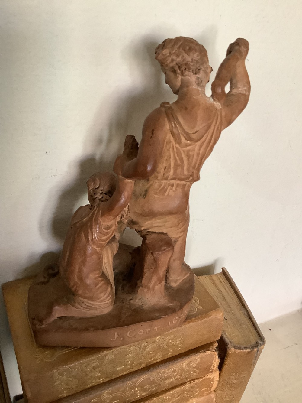 A 19th-century terracotta sculpture depicting two classical figures set on an integral oval base. View II