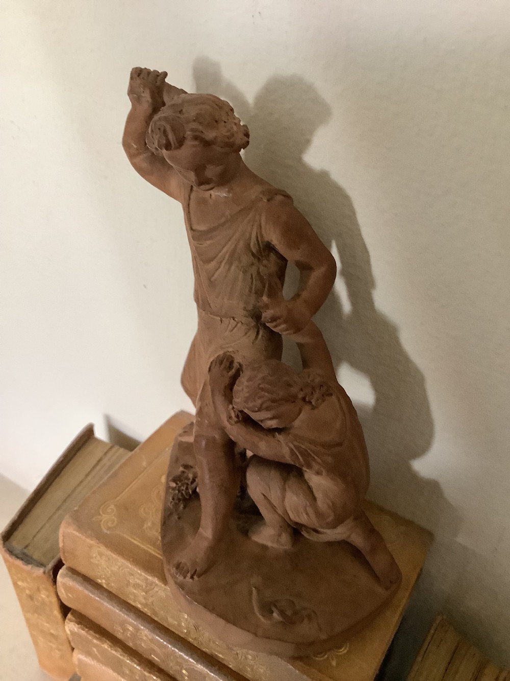 A 19th-century terracotta sculpture depicting two classical figures set on an integral oval base. View IV