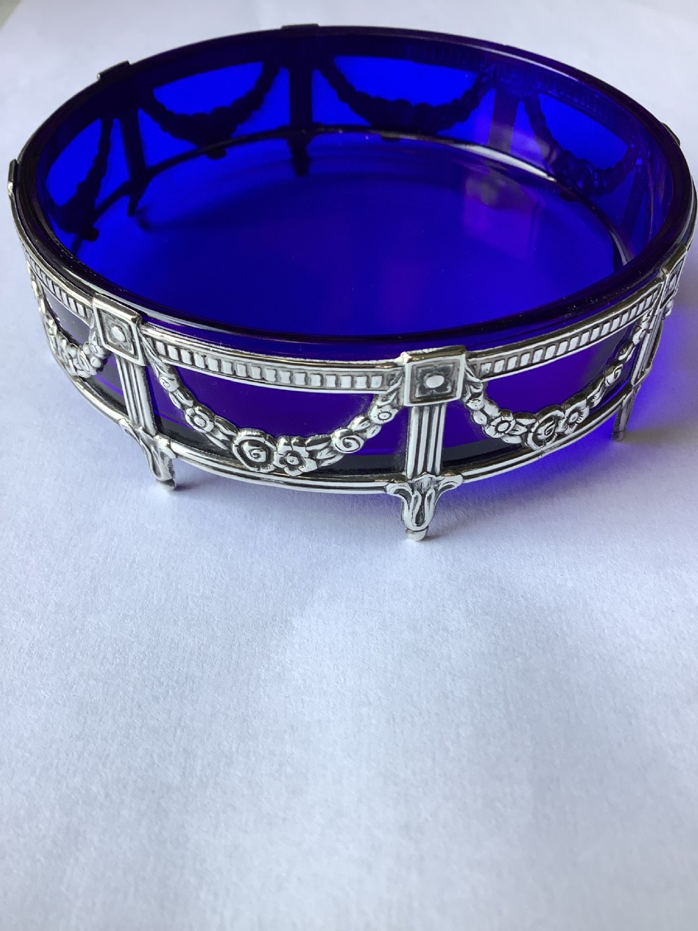 A round cobalt blue glass dish set within an Edwardian silver frame decorated with embossed floral garlands. View VII