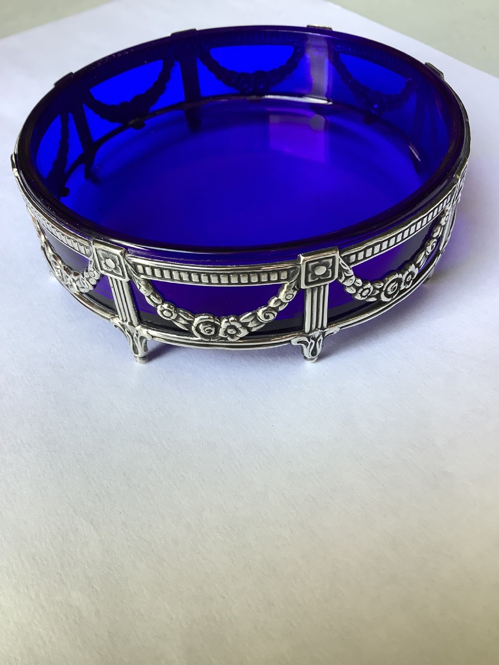 A round cobalt blue glass dish set within an Edwardian silver frame decorated with embossed floral garlands. View IX