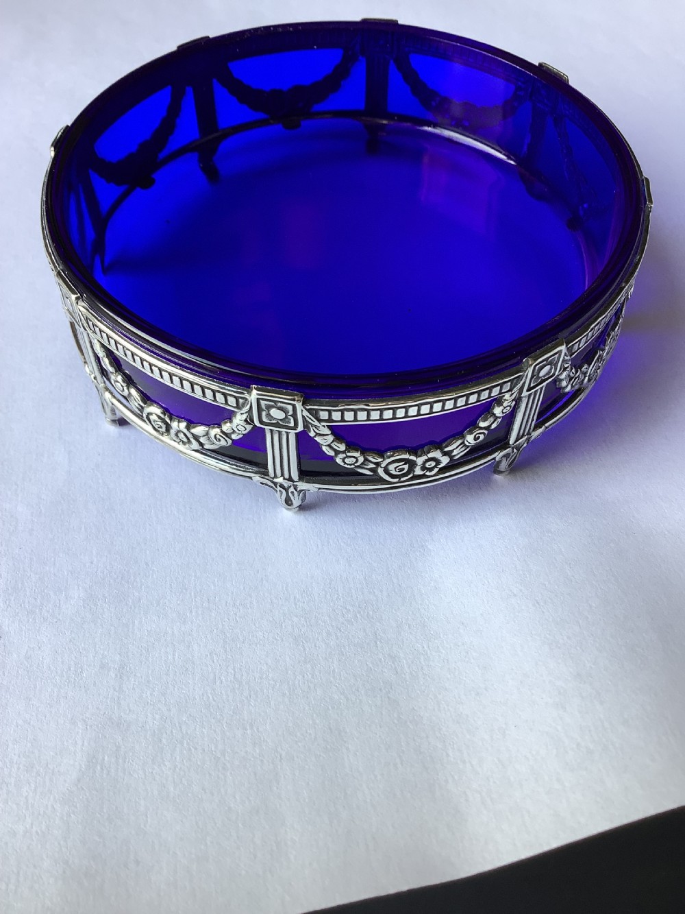 A round cobalt blue glass dish set within an Edwardian silver frame decorated with embossed floral garlands. View X