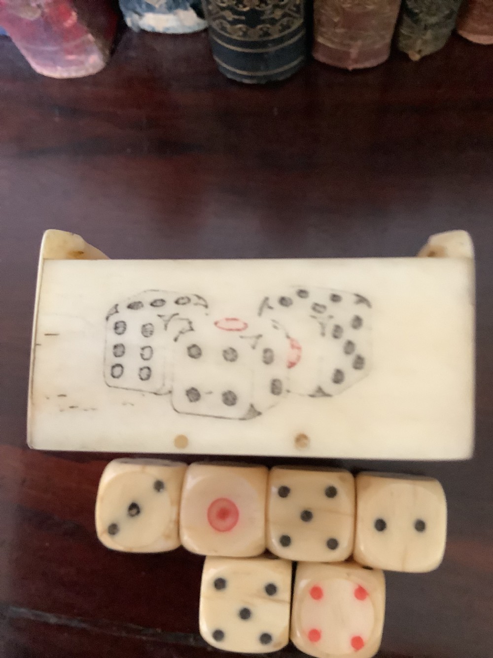 A small rectangular carved bone box containing six hand-carved bone dice with a sliding lid decorated with an etched playing card image. View V