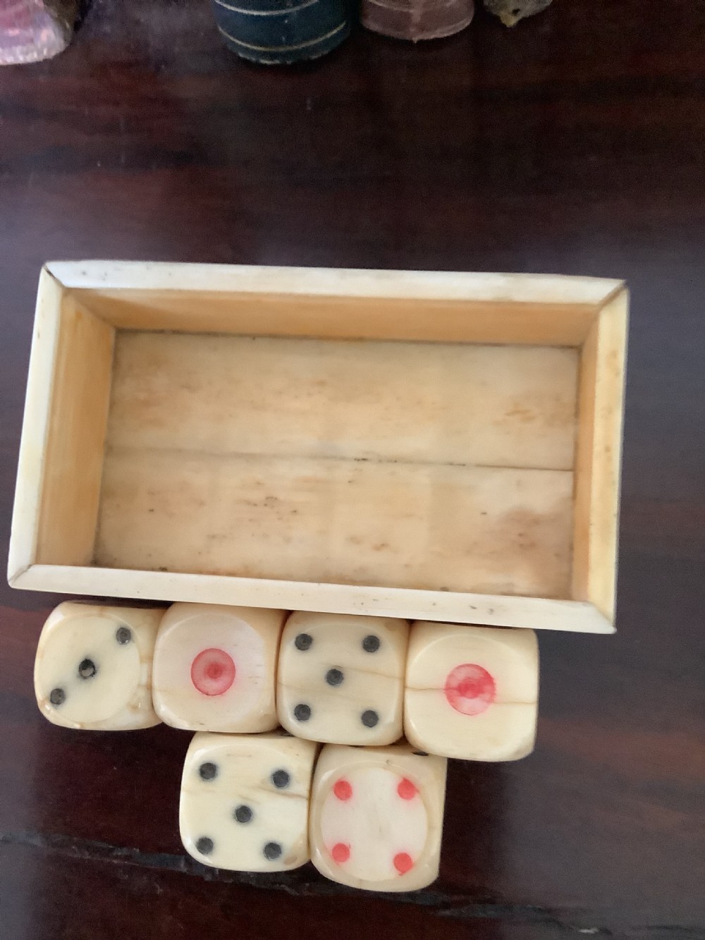 A small rectangular carved bone box containing six hand-carved bone dice with a sliding lid decorated with an etched playing card image. View VI