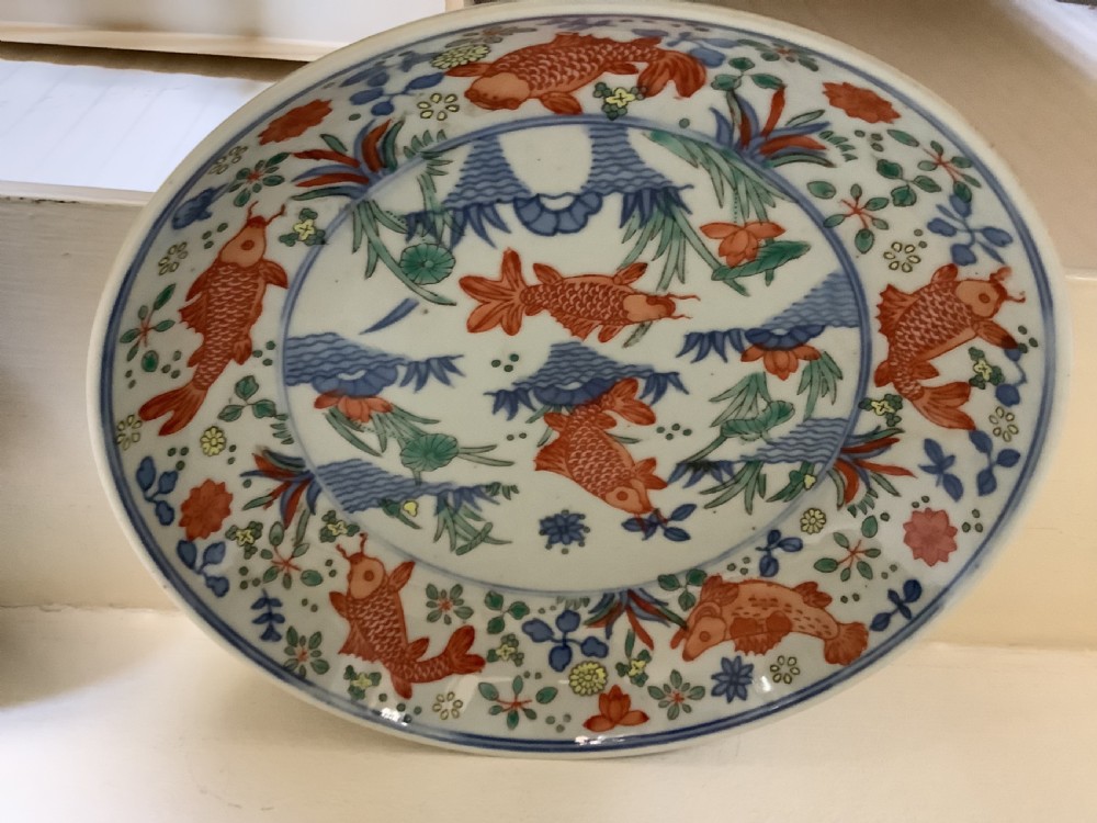 A pair of shallow circular porcelain dishes decorated with hand-painted iron-red carp and green aquatic plants inside a floral border. View II