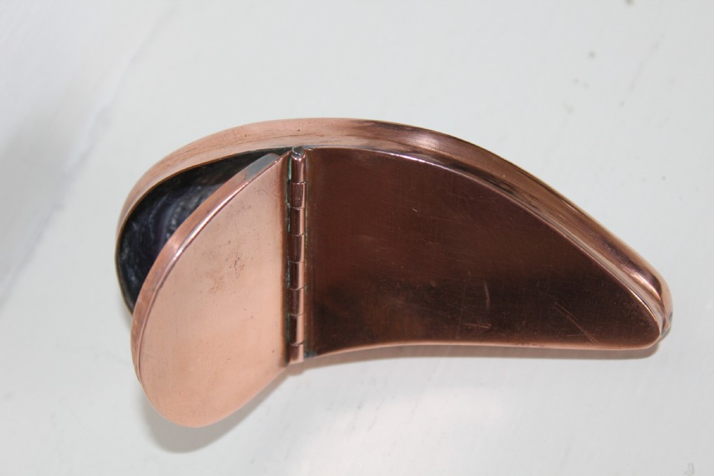 An antique mussel shell pocket snuff box with polished dark purple and brown concentric growth lines framed by a copper metal rim. View V