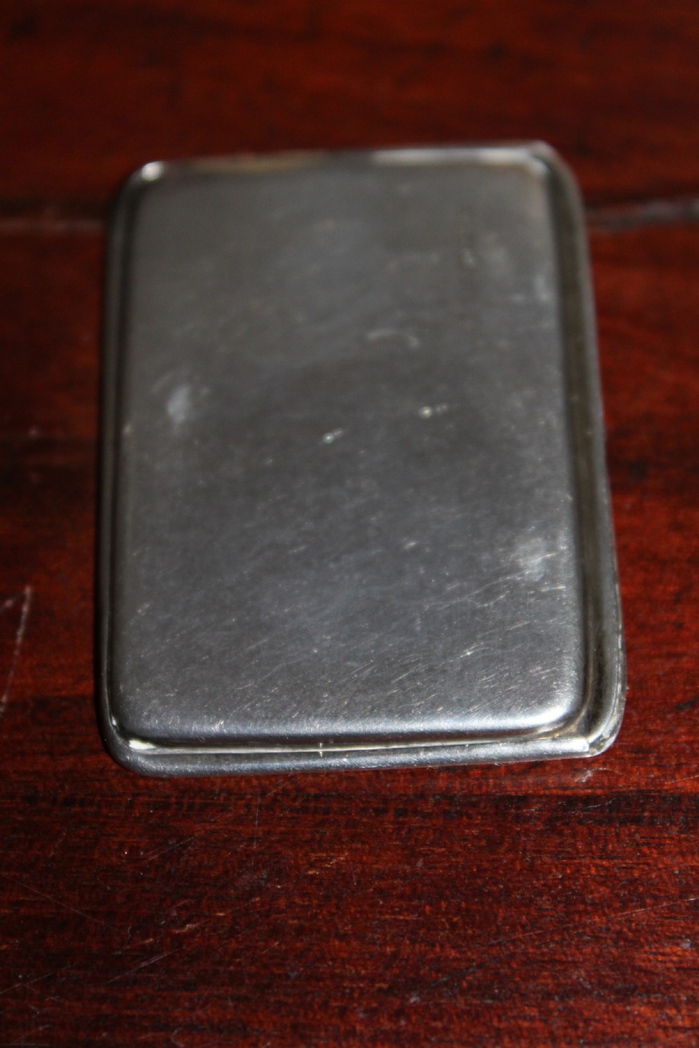 A small rectangular sterling silver stamp case featuring an engraved clover motif and a cabochon push clasp. View IV