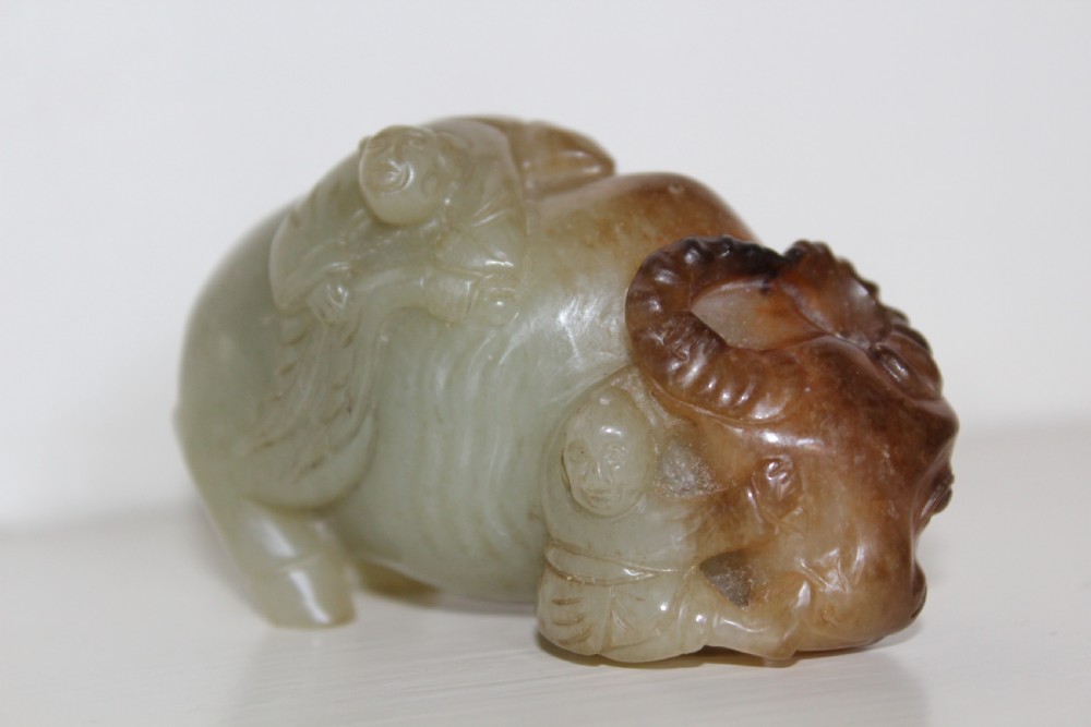 A finely carved pale green and russet jade buffalo 
