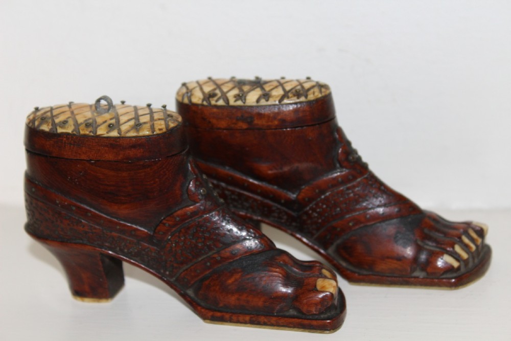 A pair of nineteenth-century carved wooden treen snuff boxes shaped like feet wearing heel shoes with bone toenails and cross-hatched inlaid lids.