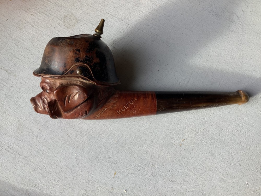 A carved wooden smoking pipe featuring a satirical pig head wearing a spiked helmet with the word Kultur inscribed on the stem. View IV
