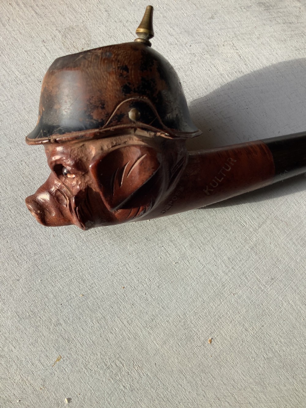 A carved wooden smoking pipe featuring a satirical pig head wearing a spiked helmet with the word Kultur inscribed on the stem. View V