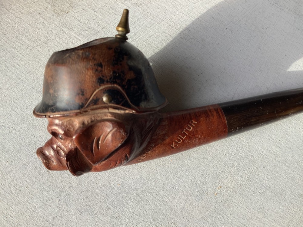 A carved wooden smoking pipe featuring a satirical pig head wearing a spiked helmet with the word Kultur inscribed on the stem. View VI