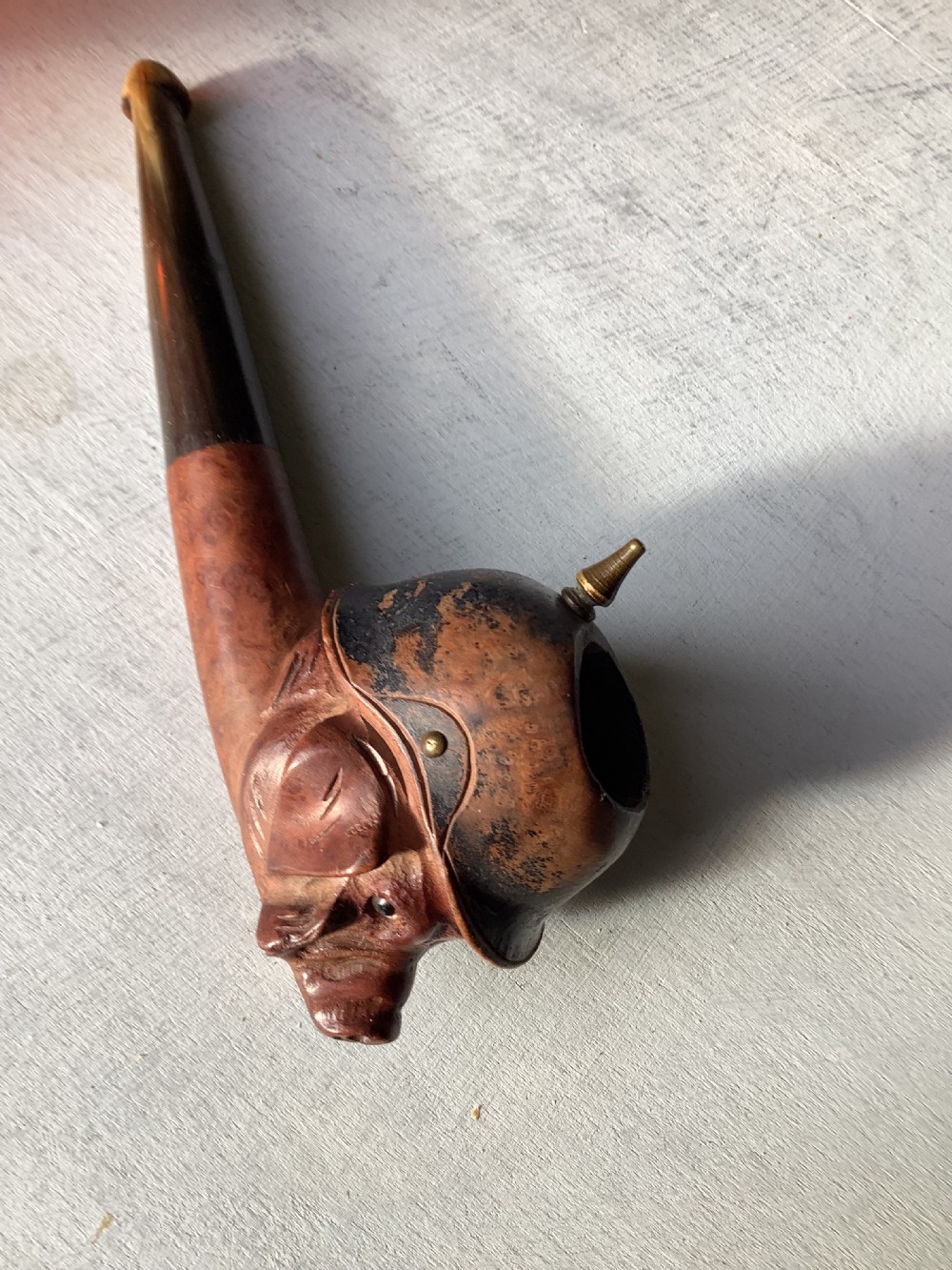 A carved wooden smoking pipe featuring a satirical pig head wearing a spiked helmet with the word Kultur inscribed on the stem. View VII