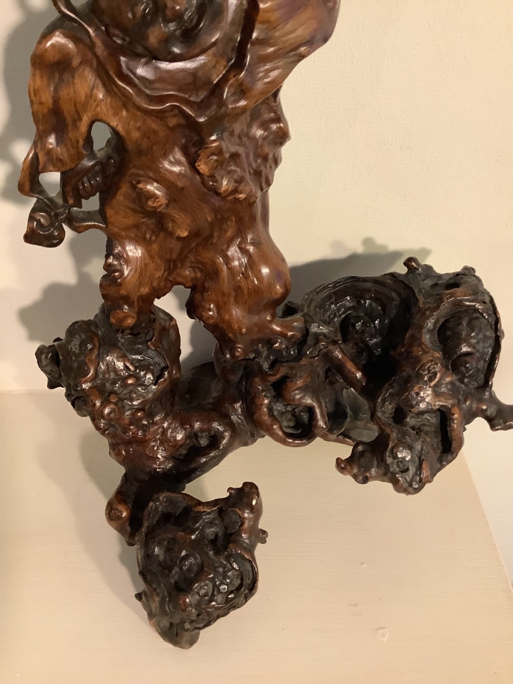 A carved dark brown rootwood sculpture depicting a smiling man carrying a child on his shoulders, integrated into the natural gnarled shape of the wood root. View V