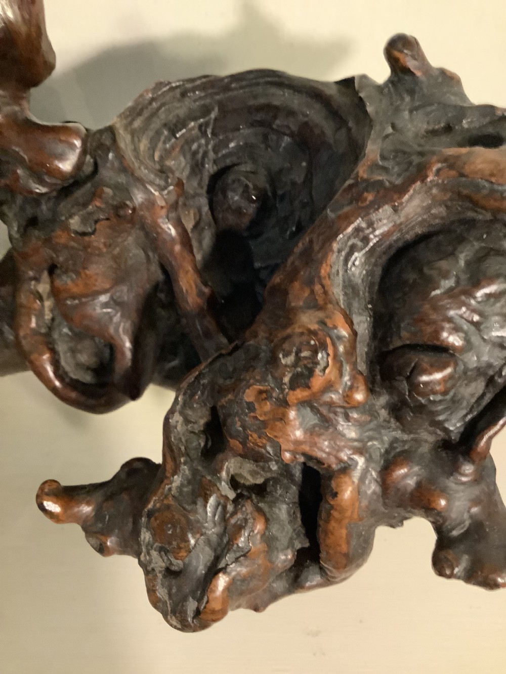 A carved dark brown rootwood sculpture depicting a smiling man carrying a child on his shoulders, integrated into the natural gnarled shape of the wood root. View VIII