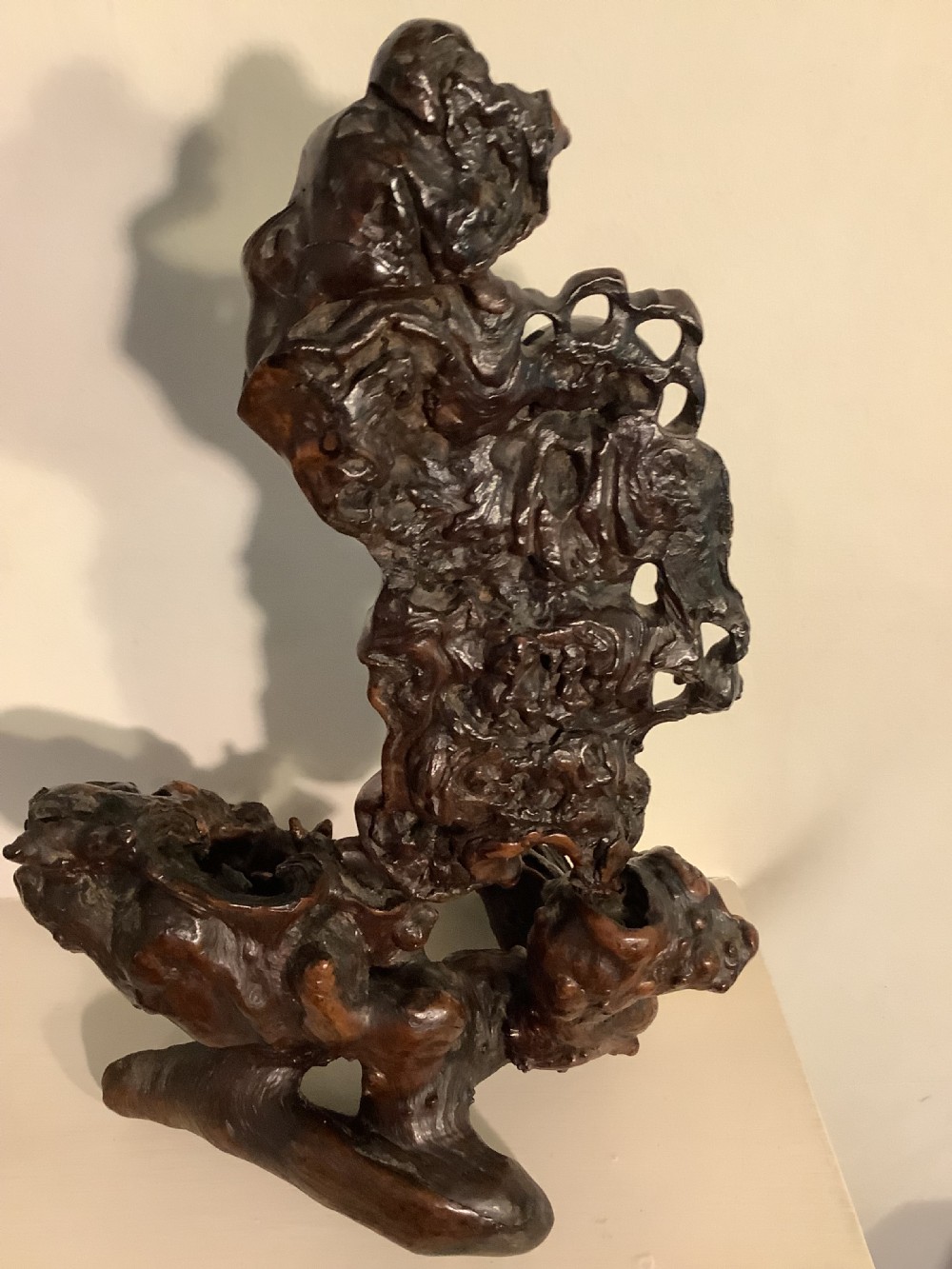 A carved dark brown rootwood sculpture depicting a smiling man carrying a child on his shoulders, integrated into the natural gnarled shape of the wood root. View X