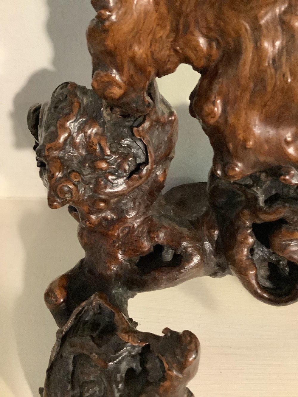 A carved dark brown rootwood sculpture depicting a smiling man carrying a child on his shoulders, integrated into the natural gnarled shape of the wood root. View XI