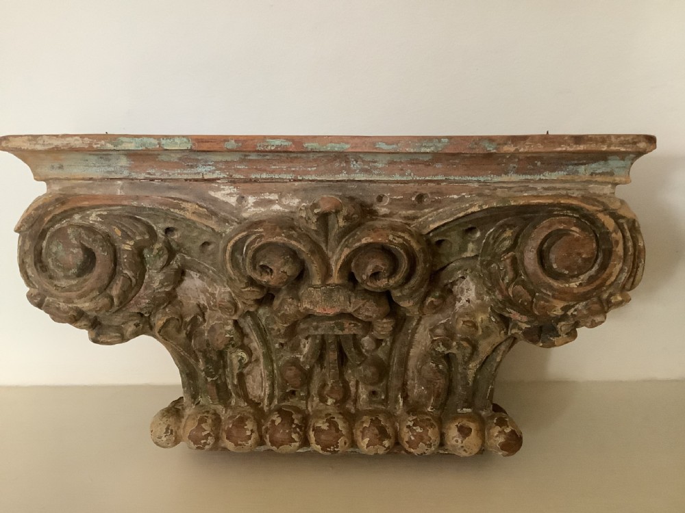 A pair of carved wooden Corinthian architectural capitals featuring acanthus leaf motifs and distressed painted finishes with metal candle inserts on top. View II