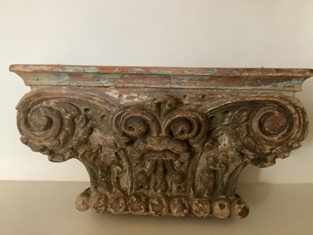 A pair of carved wooden Corinthian architectural capitals featuring acanthus leaf motifs and distressed painted finishes with metal candle inserts on top. View III